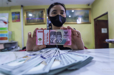 Petugas menunjukkan mata uang Rupiah dan Dolar AS di tempat penukaran uang Dolar Indo, Jakarta, Selasa (11/10/2022).
