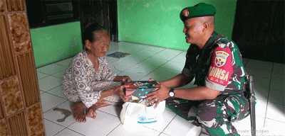 Prajurit TNI dari Kodim 1611 Badung bali memberikan sembako dari Qnet kepada warakawuri dalam acara penyerahan rumah layak huni bagi warakawuri di Badung, Bali.