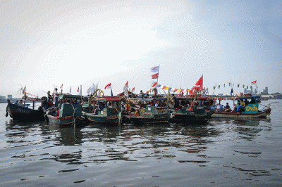 Sejumlah warga mengikuti proses pelepasan sesaji ke laut saat tradisi Nadran Pesta Laut atau Festival Kampung Nelayan di Cilincing, Jakarta Utara.
