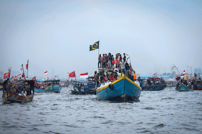 Sejumlah warga mengikuti proses pelepasan sesaji ke laut saat tradisi Nadran Pesta Laut atau Festival Kampung Nelayan di Cilincing, Jakarta Utara.