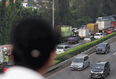 Warga mengamati lalu lintas tol jorr di kawasan Jatiwarna, Kota Bekasi, Jawa Barat, Rabu (26/10/2022).