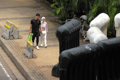 Warga berjalan di dekat barrier yang berada di trotoar di Jalan Medan Merdeka Barat, Gambir, Jakarta, Sabtu (5/11/2022).