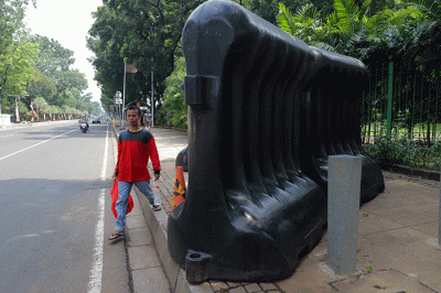 Warga berjalan di dekat barrier yang berada di trotoar di Jalan Medan Merdeka Barat, Gambir, Jakarta, Sabtu (5/11/2022).