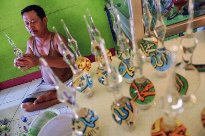 Pengrajin UMKM menyelesaikan pembuatan produk daur ulang lampu bekas menjadi neon kreasi di rumah produksi Dua Putri Souvenir Glass.