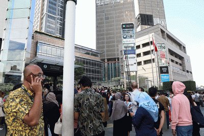 Sejumlah pekerja berhamburan keluar gedung setelah merasakan gempa di kawasan perkantoran di Jakarta, Senin (21/112022).