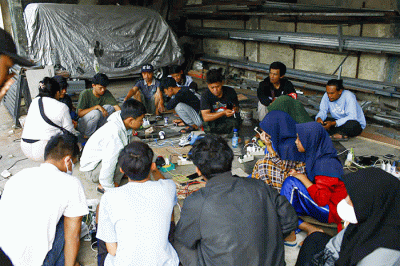 Sejumlah warga bergantian untuk mengisi daya ponselnya menggunakan genset keliling karena listrik masih padam imbas gempa bumi.