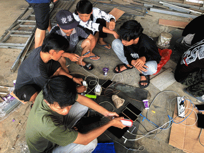 Sejumlah warga bergantian untuk mengisi daya ponselnya menggunakan genset keliling karena listrik masih padam imbas gempa bumi.