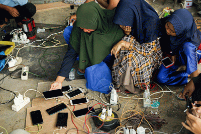 Sejumlah warga bergantian untuk mengisi daya ponselnya menggunakan genset keliling karena listrik masih padam imbas gempa bumi.