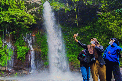 Pengunjung saat menikmati suasana keindahan air terjun curug Telu di lereng Gunung Slamet, Jawa Tengah, Minggu (27/11/2022).