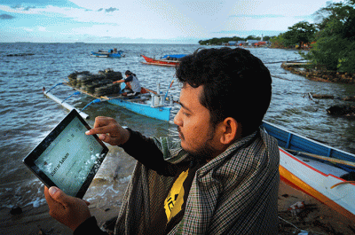 Warga tengah membuka situs Bursa Efek Indonesia untuk membuka tabungan saham syariah di Pantai Losari, Makassar.