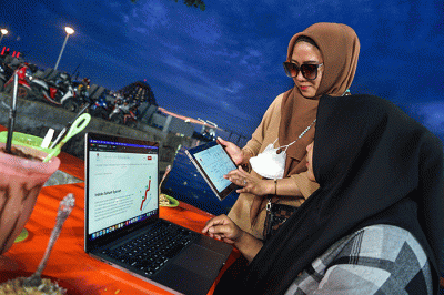 Warga tengah membuka situs Bursa Efek Indonesia untuk membuka tabungan saham syariah di Pantai Losari, Makassar.