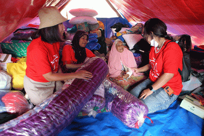 Volunteer Karyawan Prudential Indonesia berbincang dengan korban gempa usai membagikan bantuan di Desa Sukamulya, Cugenang, Kabupaten Cianjur.