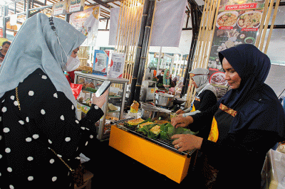Penjual menunjukkan pempek jualannya dalam acara Expo Pempek 2022 di Mal Sarinah, Jakarta Pusat, Jumat (2/12/2022).