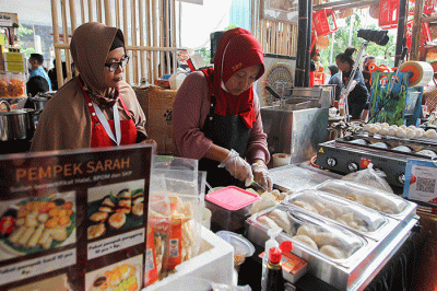 Penjual menunjukkan pempek jualannya dalam acara Expo Pempek 2022 di Mal Sarinah, Jakarta Pusat, Jumat (2/12/2022).