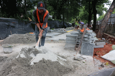 Pekerja saat menyelesaikan proyek revitalisasi trotoar di kawasan Jalan Medan Merdeka, Jakarta, Selasa (6/12/2022).