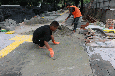 Pekerja saat menyelesaikan proyek revitalisasi trotoar di kawasan Jalan Medan Merdeka, Jakarta, Selasa (6/12/2022).