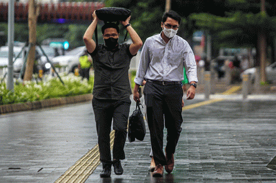Warga dengan mengunakan payung menerjang hujan saat jam pulang kerja di kawasan Jalan Jenderal Sudirman, Jakarta, Senin (12/12/2022).