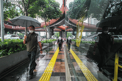 Warga dengan mengunakan payung menerjang hujan saat jam pulang kerja di kawasan Jalan Jenderal Sudirman, Jakarta, Senin (12/12/2022).