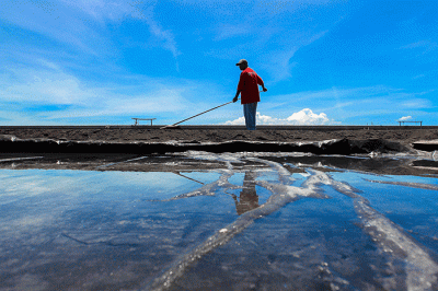 Petani saat merapikan ladang garam setelah disiram air laut di Desa Kusamba, Bali, Selasa (20/12/2022).