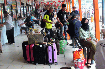 Penumpang berjalan menuju bus antarkota antarprovinsi (AKAP) di Terminal Kalideres, Jakarta Barat, Rabu (21/12/2022).