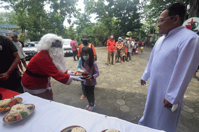 Ibu-ibu relawan Piring Kasih berbagi makan siang gratis kepada masyarakat di pelataran Gereja St Theresia Bongsari Semarang, Jawa Tengah, Kamis (22/12/2022).