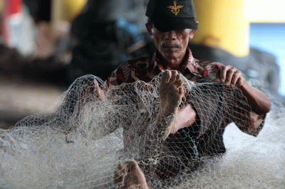Nelayan memperbaiki jaring yang rusak di Kampung Nelayan Cilincing, Jakarta, Jumat (30/12/2022).