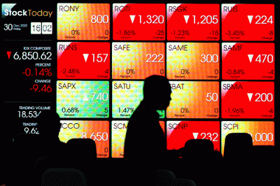Karyawan melintasi layar yang menampilkan Indeks Harga Saham Gabungan (IHSG) saat acara Penutupan Perdagangan Bursa Efek Indonesia Tahun 2022 di Jakarta.
