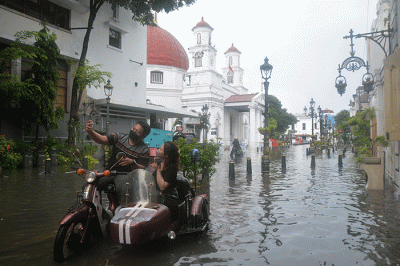 Sejumlah warga menerjang banjir yang merendam kawasan Kota Lama Semarang, Jawa Tengah, Sabtu (31/12/2022).