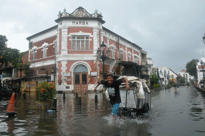Sejumlah warga menerjang banjir yang merendam kawasan Kota Lama Semarang, Jawa Tengah, Sabtu (31/12/2022).
