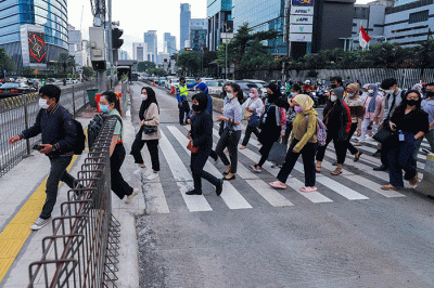Pekerja melintas saat jam pulang kerja di Kawasan Thamrin, Jakarta Pusat, Senin (2/1/2023).