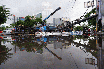 Sejumlah pekerja mengangkat reklame yang tumbang di perempatan Jalan Metro Tanjung Bunga, Makassar, Rabu (4/1/2023).