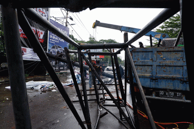 Sejumlah pekerja mengangkat reklame yang tumbang di perempatan Jalan Metro Tanjung Bunga, Makassar, Rabu (4/1/2023).