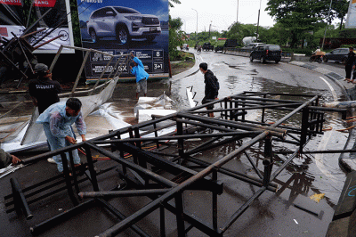 Sejumlah pekerja mengangkat reklame yang tumbang di perempatan Jalan Metro Tanjung Bunga, Makassar, Rabu (4/1/2023).