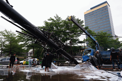 Sejumlah pekerja mengangkat reklame yang tumbang di perempatan Jalan Metro Tanjung Bunga, Makassar, Rabu (4/1/2023).