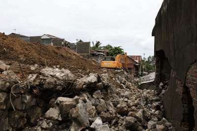Warga dan petugas melakukan pembersihan, termasuk puing-puing sisa material bangunan yang rusak akibat tanah longsor di Kota Manado.