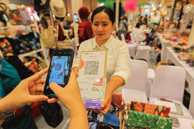 Pembeli membayar menggunakan QRIS dalam acara pameran UMKM di Jakarta, Jumat (3/2/2023).