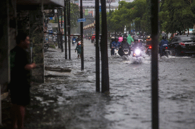 Sejumlah pengendara menerobos banjir yang menutupi jalan protokol pusat Kota Makassar, Senin (13/2/2023).