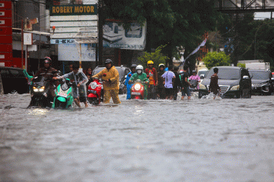 Sejumlah pengendara menerobos banjir yang menutupi jalan protokol pusat Kota Makassar, Senin (13/2/2023).
