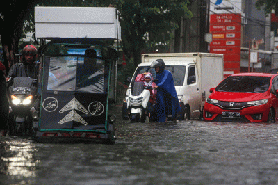 Sejumlah pengendara menerobos banjir yang menutupi jalan protokol pusat Kota Makassar, Senin (13/2/2023).