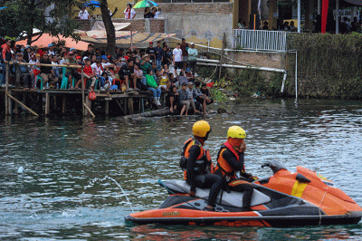 Warga menyaksikan Kejuaraan Dunia Perahu Motor F1 PowerBoat (F1H2O) di pinggir Danau Toba, Balige, Sumatera Utara, Minggu (26/2/2023).