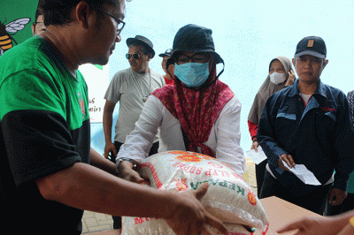 Warga menerima bantuan beras seberat 10 kg di kawasan Serdang Kemayoran, Jakarta, Sabtu (18/3/2023).