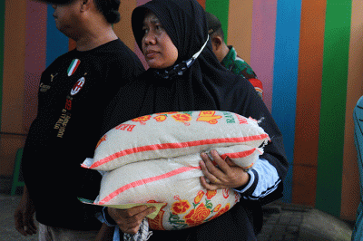 Warga menerima bantuan beras seberat 10 kg di kawasan Serdang Kemayoran, Jakarta, Sabtu (18/3/2023).
