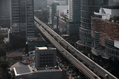 Pekerja melihat permukiman warga dan gedung bertingkat di Jakarta, Jumat (24/3/2023).