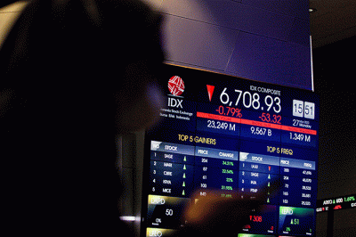Pekerja berdiri di depan layar pergerakan Indeks Harga Saham Gabungan (IHSG) di Bursa Efek Indonesia (BEI), Jakarta, Senin (27/3/2023).