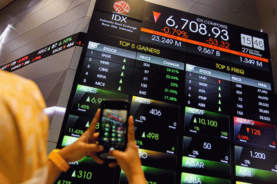 Pekerja berdiri di depan layar pergerakan Indeks Harga Saham Gabungan (IHSG) di Bursa Efek Indonesia (BEI), Jakarta, Senin (27/3/2023).