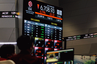 Pekerja berdiri di depan layar pergerakan Indeks Harga Saham Gabungan (IHSG) di Bursa Efek Indonesia (BEI), Jakarta, Senin (27/3/2023).