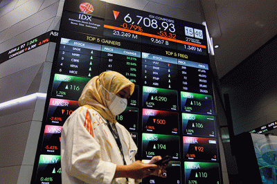 Pekerja berdiri di depan layar pergerakan Indeks Harga Saham Gabungan (IHSG) di Bursa Efek Indonesia (BEI), Jakarta, Senin (27/3/2023).