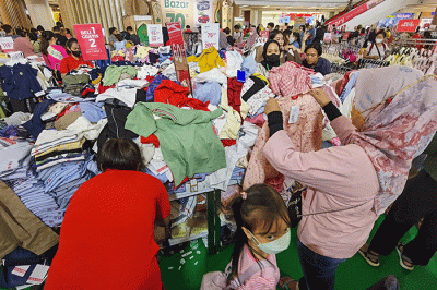 Pengunjung saat memilih pakaian yang dijual diskon di Pusat Perbelanjaan, Jakarta, Minggu (2/4/2023).