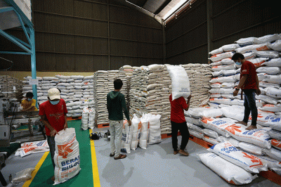 Petugas mengemas beras di gudang Bulog, Jakarta, Jumat (14/4/2023).