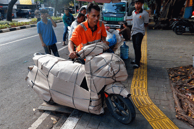 Pekerja tengah mengepak sepeda motor yang akan di kirim melalui jasa pengiriman dengan kereta api di Kawasan Stasiun Senen, Jakarta, Senin (17/4/2023).